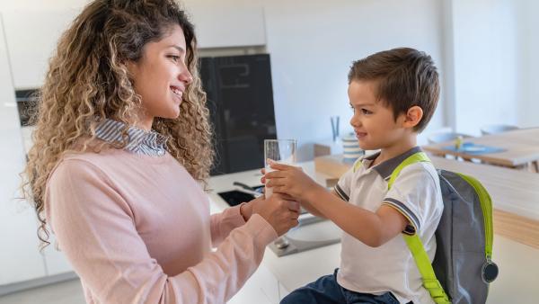 Mother handing a glass of milk to her son