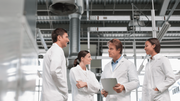 image of four lab workers in lab coats, in conversation