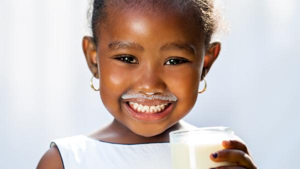 image of smiling child holding a glass of milk