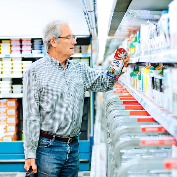 Elderly man reviewing the nutritional content of a carton of Avonmore Supermilk
