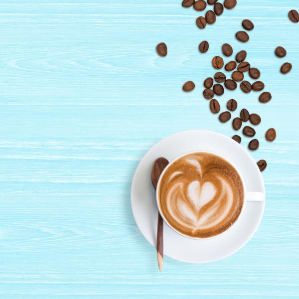 Cup of white coffee with heart patten in milk on a blue background