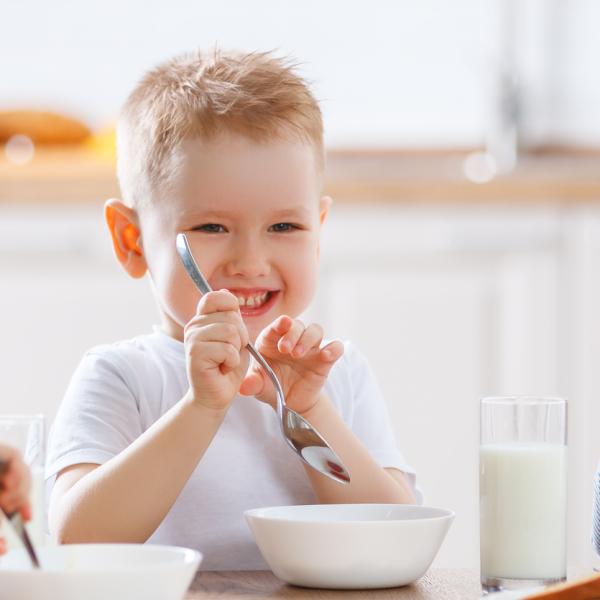 Three children sitting at breakfast table laughing