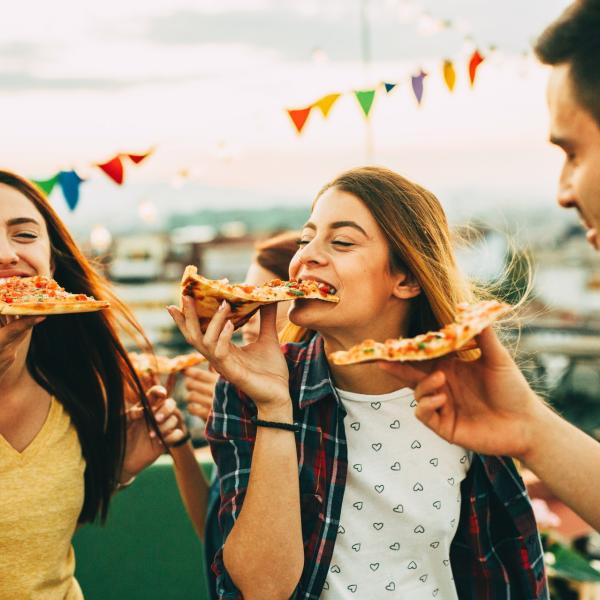 3 young adults eating pizza at a festival