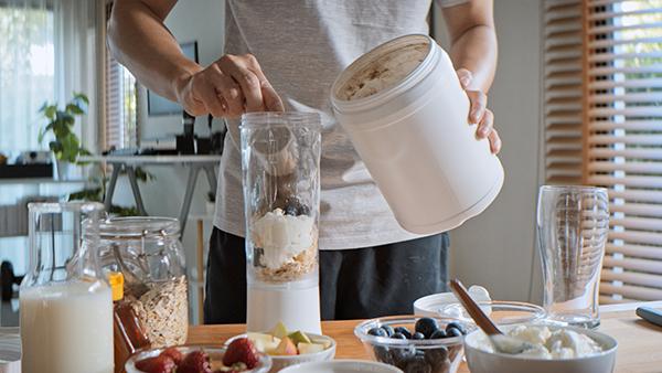 women putting rtm powder in smoothie