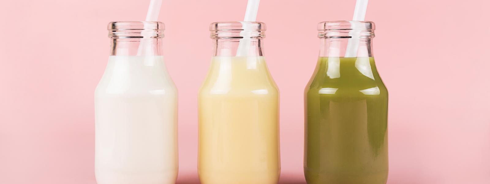 Three meal replacement drinks of different colours in small glass bottles