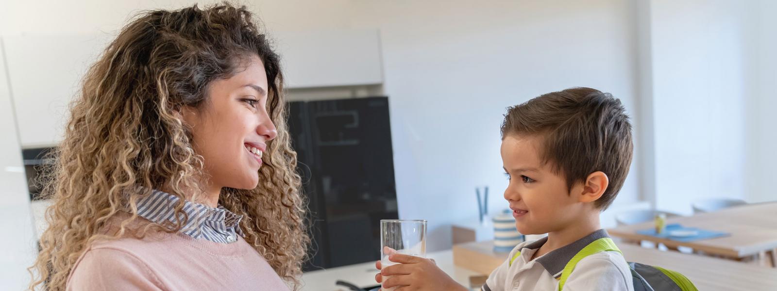 Mother handing a glass of milk to her son