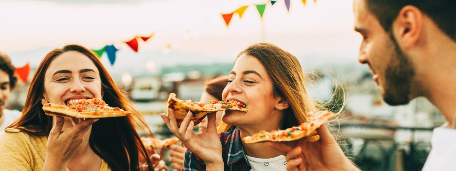 3 young adults eating pizza at a festival