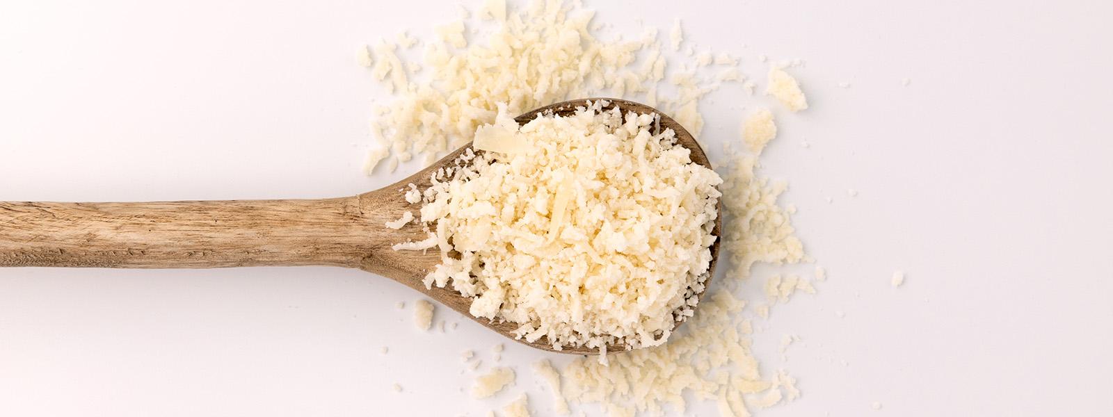 wooden spoon full of grated cheese